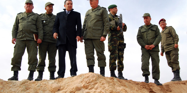 Tunisian Defense minister Farhat Horchani, third left, with Chief of Staff of the Army Ismael Fathalli, center, attend a presentation of the anti-jihadi fence, in near Ben Guerdane, eastern Tunisia, close to the border with Libya, Saturday, Feb. 6, 2016. Tunisia's defense minister has visited an anti-jihadi fence that's being built on the country's border with Libya to stop Islamist militants from entering Tunisian territory. Defense Minister Farhat Horchani inspected the first completed part of