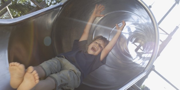 Boy sliding down slide at playground