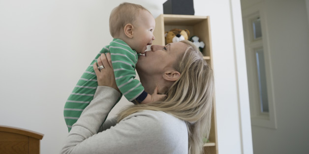 Mother kissing and cuddling happy baby boy