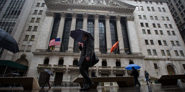 Pedestrians carry umbrellas while walking past the New York Stock Exchange (NYSE) in New York, U.S., on Wednesday, Feb. 24, 2016. U.S. stocks rose, benchmark indexes climbing back from declines of more than 1 percent as crude stabilized near $32 a barrel in New York. Photographer: Michael Nagle/Bloomberg via Getty Images