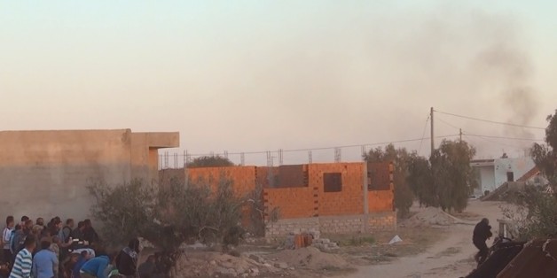 People shelter from the gun fire outside a house, in El Aouija, outside Ben Guerdane, 650 km away from Tunis, Wednesday, March 2, 2016. Tunisian security forces killed five heavily armed men in an hours-long firefight Wednesday after they crossed into the country from Libya with a larger group. (AP Photo)