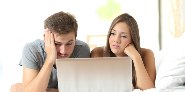 Bored marriage watching media in a laptop lying on a bed at home