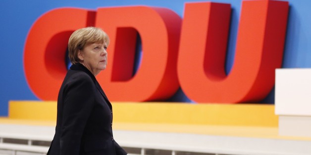 German Chancellor Angela Merkel walks past the party logo during a party convention of the Christian Democrats (CDU) in Karlsruhe, Germany, Monday, Dec. 14, 2015. (AP Photo/Michael Probst)