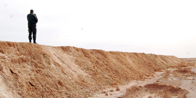 A Tunisian soldier stands on a sandbank during a presentation of the anti-jihadi fence, in near Ben Guerdane, eastern Tunisia, close to the border with Libya, Saturday, Feb. 6, 2016. Tunisia's defense minister has visited an anti-jihadi fence that's being built on the country's border with Libya to stop Islamist militants from entering Tunisian territory. Defense Minister Farhat Horchani inspected the first completed part of the 196-kilometer (122-mile) fence Saturday, which aims to counter the