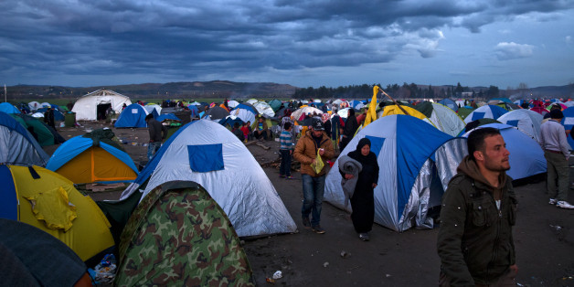 Migrants stand next to tents during rainfall at the northern Greek border station of Idomeni, Friday, March 4, 2016. More than 10,000 mostly Syrian and Iraqi refugees were stuck at the country's Idomeni border as Greek officials said that nearly 32,000 migrants were stranded in the country after drastically reduce of number of transiting migrants. (AP Photo/Vadim Ghirda)