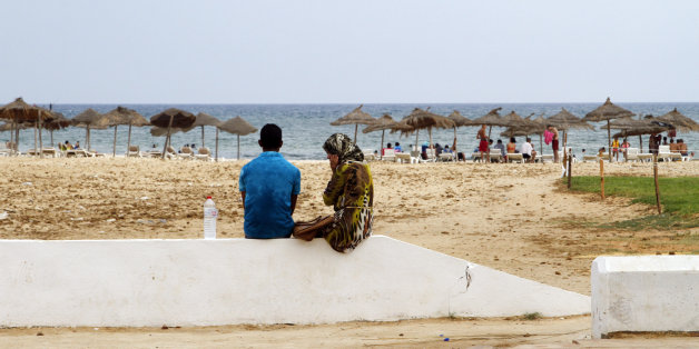 In this photo taken on Aug. 9, 2015, a Tunisian couple sit on the sea wall watching the beach in Hammamet, Tunisia. The jet skis roar by the shore and the water is full of splashing children along the Tunisian Riviera, where despite the deadly attack that killed 38 tourists in June, the beaches are still full _ for now. Europeans have abandoned this North African country, leaving just local Tunisian beach-goers and visiting Algerians. But they will be gone by monthâs end, and then the real
