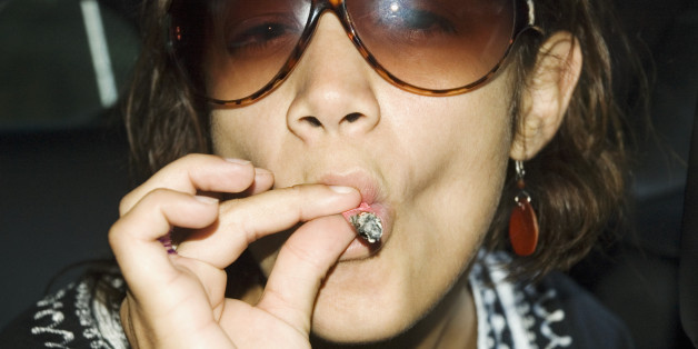 Close-up of young woman in sunglasses smoking a marijuana joint