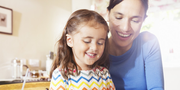 mother shows young child to use digital tablet