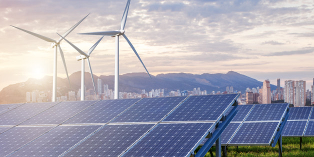 solar panels and wind turbines under sky and clouds with city on horizon. Sunrise