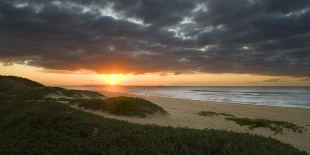 Hawaiian sunset at the miles long Polihale beach on the island of Kauai, Hawaii, USA. The island of Nihau can be seen under the setting sun.
