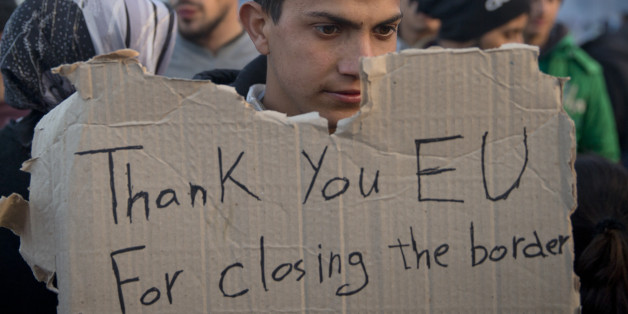 A migrant holds an improvised banner after news of the Brussels summit agreement reached the inhabitants of the make shift refugee camp at the northern Greek border point of Idomeni, Greece, Friday, March 18, 2016. More than 46,000 people are trapped in Greece, after Austria and a series of Balkan countries stopped letting through refugees who reach Greece from Turkey and want to go to Europe's prosperous heartland while Greece wants refugees to move from Idomeni to organized shelters. (AP Photo/Vadim Ghirda)
