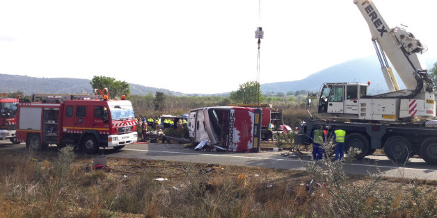 Emergency services personnel stand at the scene of a bus accident crashed on the AP7 highway that links Spain with France along the Mediterranean coast near Freginals halfway between Valencia and Barcelona early Sunday, Spain, March 20, 2016. The bus was reportedly hired out to carry students to and from a fireworks festival in Valencia and was on the return leg of its journey when the accident happened. (AP Photo)