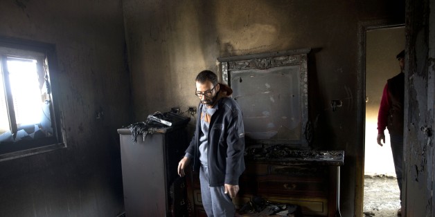 A Palestinian man inspects a house that was torched in the Palestinian village of Duma near the West Bank city of Nablus, Sunday, March 20, 2016. A Palestinian home near the site of an arson attack that killed three Palestinians last year caught fire early Sunday, Israeli and Palestinian officials said, with immediate suspicion falling on Jewish extremists. (AP Photo/Majdi Mohammed)