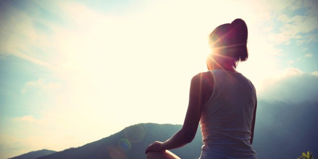 young yoga woman at sunrise mountain peak