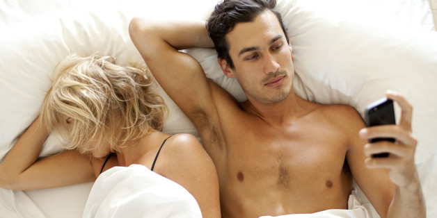 Man texting SMS on mobile phone in bed
