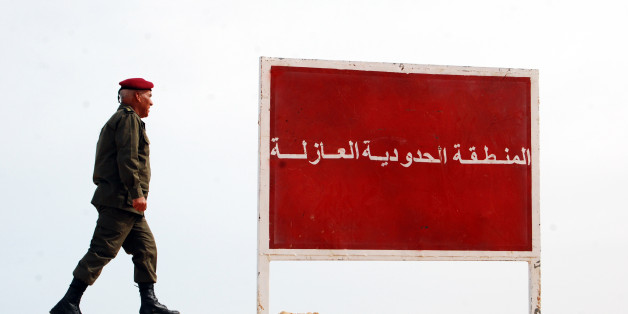 A Tunisian soldier walks on a sandbank near a board saying "no-man's land, buffer zone" during a presentation of the anti-jihadi fence, in near Ben Guerdane, eastern Tunisia, close to the border with Libya, Saturday, Feb. 6, 2016. Tunisia's defense minister has visited an anti-jihadi fence that's being built on the country's border with Libya to stop Islamist militants from entering Tunisian territory. Defense Minister Farhat Horchani inspected the first completed part of the 196-kilometer (122-mile) fence Saturday, which aims to counter the threat from jihadi militants and render the entire border impassable by vehicles. Horchani said the project came about with financial assistance from Germany and the U.S. (AP Photo/Benjamin Wiacek)