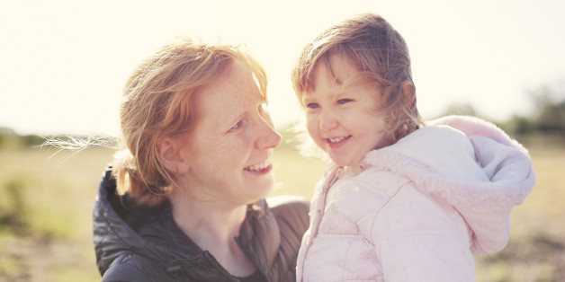 A happy mother and daughter in a park backlit by autumn sunshine.