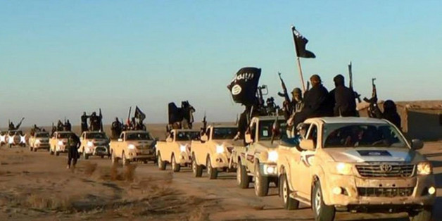 FILE - In this undated file photo released online in the summer of 2014 on a militant social media account, which has been verified and is consistent with other AP reporting, militants of the Islamic State group hold up their weapons and wave its flags on their vehicles in a convoy on a road leading to Iraq, in Raqqa, Syria. (Militant photo via AP, File)