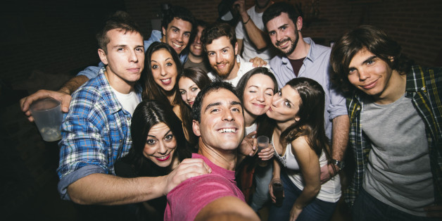 Smiling friends taking selfie in nightclub