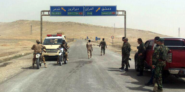 In this photo released by the Syrian official news agency SANA, Syrian government soldiers gather at the entrance of the town of Palmyra, central Syria, Thursday, March 24, 2016. Syrian government forces pushed into the ancient town of Palmyra, where Islamic State militants appeared on the verge of collapse Thursday, while in Iraq, a military spokesman announced the start of a long-awaited operation to recapture the IS-held northern city of Mosul. (SANA via AP)