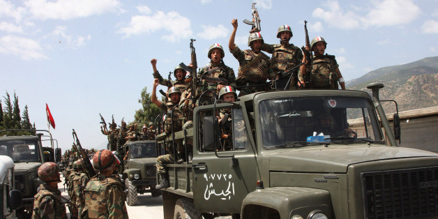 FILE - In this file photo taken on Friday, June 10, 2011, during a government organized tour for the media, shows Syrian army soldiers standing on their military trucks chanting slogans in support of Syrian President Bashar Assad, as they enter a village near the town of Jisr al-Shughour, north of Damascus, Syria. (AP Photo, File)