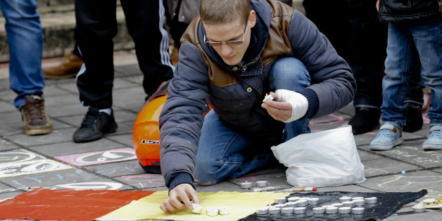 BRUSSELS, March 23, 2016 -- A man lights candles on top a Belgian flag to mourn the victims in downtown Brussels, Belgium, March 23, 2016. At least 34 people were killed and 180 injured after explosions at Brussels airport and a metro station on Tuesday. (Xinhua/Ye Pingfan via Getty Images)