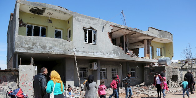 People stand in front of a building, which was damaged during the security operations and clashes between Turkish security forces and Kurdish militants, in the southeastern town of Idil, Turkey, March 31, 2016. REUTERS/Sertac Kayar