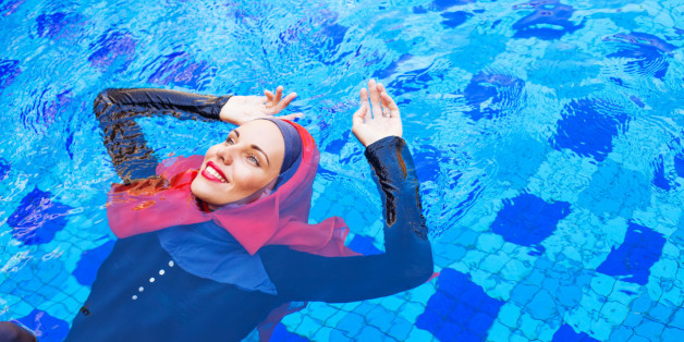 muslim woman in red hijab swimming in a pool (lying on a back)