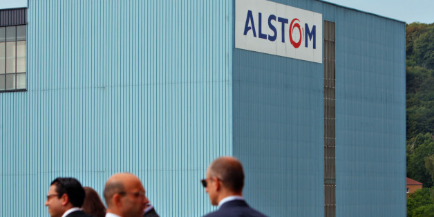 People chat in front of the Alstom plant in Belfort, eastern France, Tuesday, June 24, 2014. Alstom's chief executive said the French heavy engineering firm's agreement to sell off most of its power generation business to U.S. rival General Electric Co. will save jobs and protect France's national interests. The $17 billion deal was agreed over the weekend after weeks of international negotiations that reached the highest levels of French politics. (AP Photo/Thibault Camus)