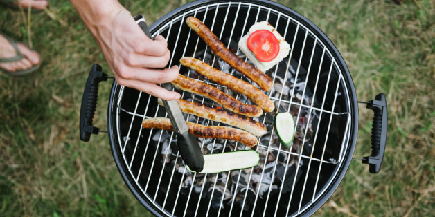 Hand at barbeque grill with sausages grill cheese and zucchini