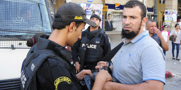 Tunisian police checks a demonstrator during a march under heavy security to protest a law offering amnesty for those accused of corruption, in Tunis, Tunisia, Saturday Sept. 12, 2015. The controversial draft law on economic reconciliation is a centerpiece of the new government's program and seeks to boost the economy by clearing cases against businessmen and civil servants accused of corruption. (AP Photo/Riadh Dridi)