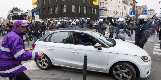 A Belgian police officer points his gun while riot police use their truncheons at a car driving towards a police road block before it hit and injured a woman on the street in the Brussels district of Molenbeek, Belgium, April 2, 2016. REUTERS/Yves Herman