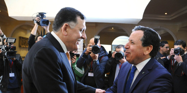 Tunisian Foreign Minister Khemaies Jhinaoui, right, shakes hands with Libyan prime minister Fayez Sarraj, before a foreign ministers meeting on Libya's neighbors, Tuesday, March 22, 2016 outside Tunis. A unity government in Libya has been nominated under a UN-sponsored plan, but has not won approval yet. (AP Photo/Hassene Dridi)