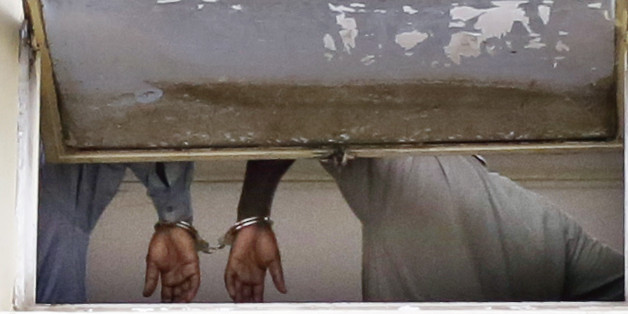 ALTERNATIVE RECROP OF XJD110--Two soldiers accused of taking part in the fizzled coup attempt are handcuffed together as they face charges in the courtroom in Bujumbura, Burundi, Saturday May 16, 2015. Topless, barefoot and with wounds from alleged torture seventeen security officials, including five generals appeared before a prosecutor who is expected to file treason charges against them over the attempted coup of President Pierre Nkurunziza, lawyers of some of the suspects said Saturday. (AP Photo/Jerome Delay)
