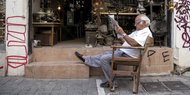 A vendor reads newspaper in front of his shop in Athens, Greece June 27, 2015. Greek Prime Minister Alexis Tsipras called a referendum on bailout demands from foreign creditors on Saturday, rejecting an "ultimatum" from lenders and putting a deal that could determine Greece's future in Europe to a risky popular vote. REUTERS/Marko Djurica