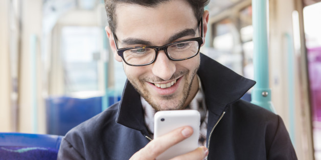 man sitting in public transport looking at phone.