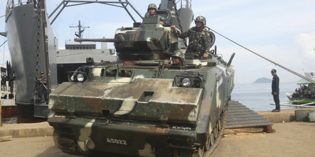 Filipino soldiers aboard an armoured vehicle roll off from a Philippine Navy ship after arriving in Jolo, Sulu southern Philippines October 16, 2014. The Philippines on Thursday stepped up army patrols in the jungles of the southern island of Jolo where al Qaeda-linked Islamist militants are holding two Germans captive and are threatening to kill one of them. The militants from the Abu Sayyaf group have demanded a 250 million pesos ($5.6 million) ransom and for Germany to stop supporting U.S.-le