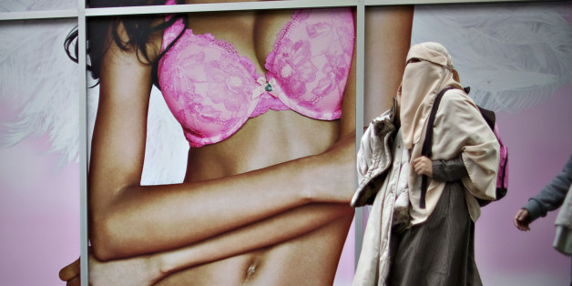 A Muslim woman wearing a hijab walks past a lingerie advertisement in downtown Vancouver, British Columbia April 26, 2013. REUTERS/Andy Clark (CANADA - Tags: SOCIETY)