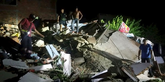 People stand next to the debris of a building after a 7.8 magnitude earthquake struck off the country's northwest Pacific coast causing "considerable damage", in Manta, Ecuador, April 16, 2016. REUTERS/Patricio Ramos EDITORIAL USE ONLY. NO RESALES. NO ARCHIVE TPX IMAGES OF THE DAY