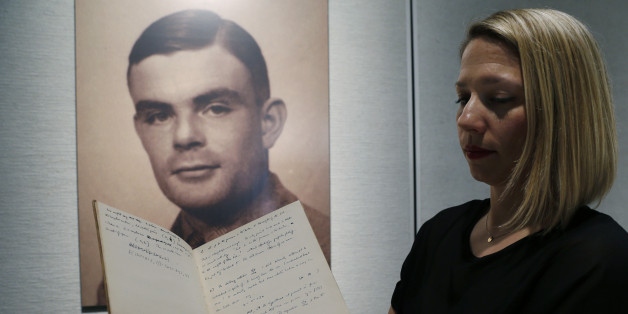 Cassandra Hatton, a senior specialist in fine books and manuscripts and director of the history of science at Bonhams auction house, shows a notebook of British mathematician and pioneer in computer science Alan Turing, the World War II code-breaking genius, in front of his portrait during an auction preview in Hong Kong Thursday, March 19, 2015. The 56-page manuscript, containing Turing's complex mathematical and computer science notations, is being sold by Bonhams in New York on April 13 and expected to bring at least US$1 million. (AP Photo/Kin Cheung)