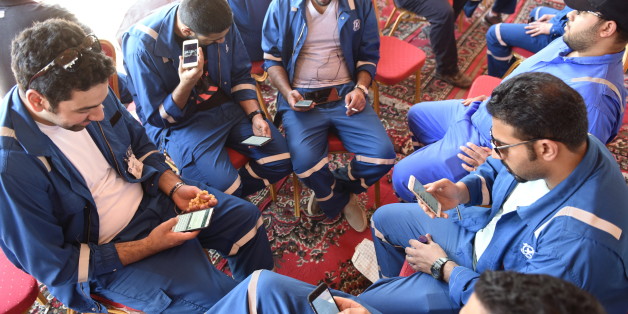 Kuwait Oil and Petrochemical Industries Union workers sit with their cellphones on the first day of an official strike over public sector pay reforms, in Ahmadi, Kuwait April 17, 2016. REUTERS/Stephanie McGehee