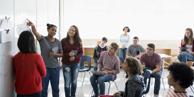 High school students giving presentation whiteboard in classroom
