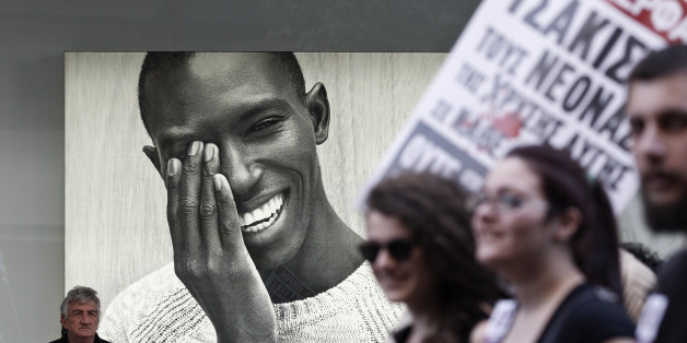 Protesters march past an advertising poster during an anti-racism rally in Athens, March 22, 2014. Thousands of protesters participated in an anti-racism rally marking the International Day for the Elimination of Racial Discrimination which is celebrated every year on March 21. REUTERS/Alkis Konstantinidis (GREECE - Tags: POLITICS SOCIETY IMMIGRATION CIVIL UNREST)