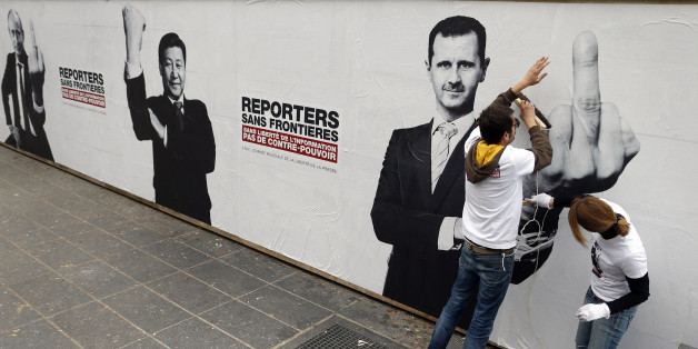 Activists from Reporters Without Borders (RSF) paste a poster depicting Russia's President Vladimir Putin (L) and his counterparts from China, Xi Jinping (C) and Syria, Bashar al-Assad, on the Brancusi Atelier to mark the 20th annual World Press Freedom day in Paris May 3, 2013. The slogan reads, "Without freedom of information, no counter-power". REUTERS/Benoit Tessier (FRANCE - Tags: POLITICS CIVIL UNREST MEDIA) TEMPLATE OUT
