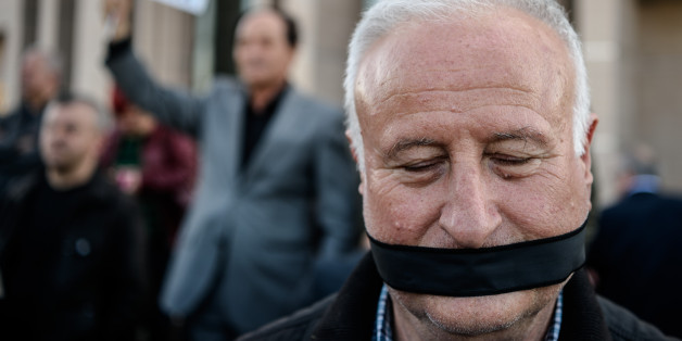 TOPSHOT - A demonstrator with his mouth covered, stands outside the Istanbul courthouse on April 1, 2016, where Turkish opposition Cumhuriyet daily's editor-in-chief Can Dundar and Ankara bureau chief Erdem Gul attend their trial.
Cumhuriyet daily's editor-in-chief Can Dundar and Ankara bureau chief Erdem Gul face possible life terms on spying charges over a news report accusing President Recep Tayyip Erdogan's government of seeking to illicitly deliver arms bound for neighbouring Syria. / AFP / OZAN KOSE (Photo credit should read OZAN KOSE/AFP/Getty Images)