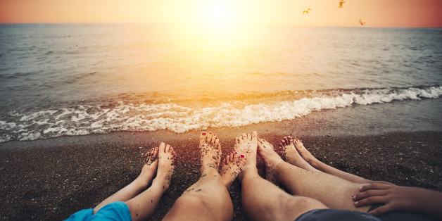 family of four relaxing on beach at sunset