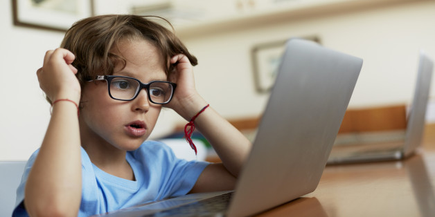 Little boy using laptop at table in house