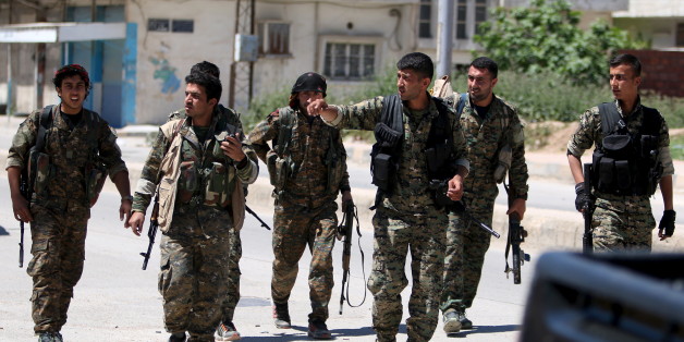 Kurdish fighters from the People's Protection Units (YPG) walk along a street in the southeast of Qamishli city, Syria, April 22, 2016. REUTERS/Rodi Said