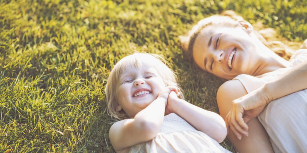 Smiling mother and baby laying on meadow