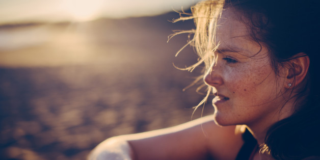 Portrait of a blond haired woman with smartwatch at the beach after running.
